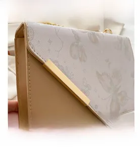 Détail du sac carré bicolore avec rabat à motif floral et bandoulière en chaîne dorée