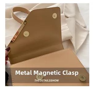 Détail du fermoir magnétique doré sur sac à bandoulière en cuir beige avec coutures fines