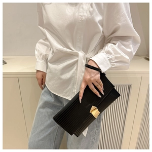 Detail of black pleated crossbody bag featuring a unique irregular gold metal buckle clasp