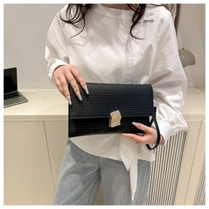 Close-up of black envelope clutch with horizontal texture and geometric metal clasp