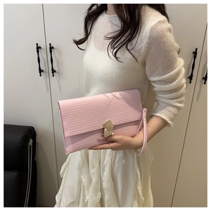 Detailed close-up of pink envelope clutch with gold buckle and wavy leather texture