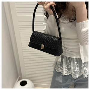 Détail du sac porté épaule tressé noir avec fermoir doré et texture élégante