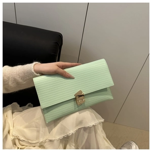 Close-up of mint green envelope clutch with textured stripes and gold metal clasp