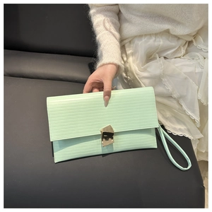 Detail of mint green envelope clutch with horizontal texture and gold geometric clasp