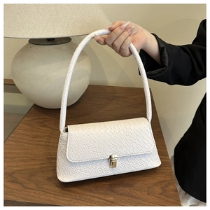 Détail d'un sac sous le bras blanc à motif crocodile avec fermoir doré élégant