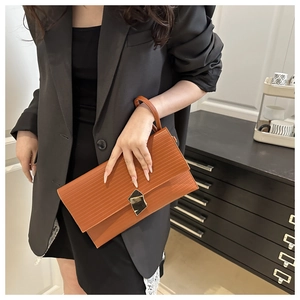 Detail of a brown rectangular envelope clutch with vertical texture and metal buckle