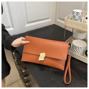 Detailed view of caramel cross-textured envelope clutch with golden geometric clasp