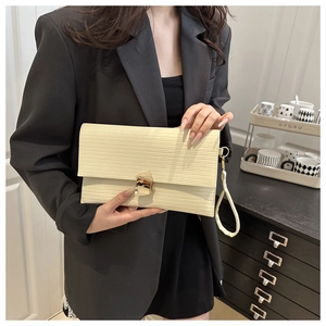 Detail of cream rectangular clutch bag with water ripple texture and gold metal buckle
