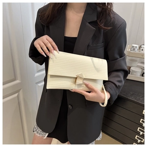 Detail of cream-white water ripple textured clutch bag with gold buckle on black blazer