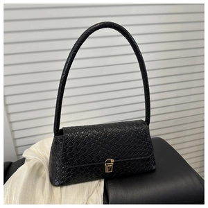 Détail de la texture tissée noire et du fermoir en métal doré d'un sac compact carré