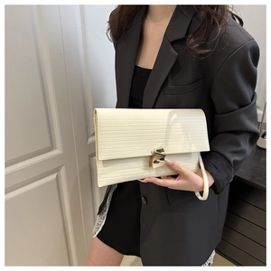 Detail of cream envelope clutch with horizontal texture and gold geometric buckle
