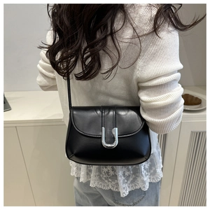 Detail of a vintage black leather crossbody bag featuring a shiny silver U-shaped metal buckle