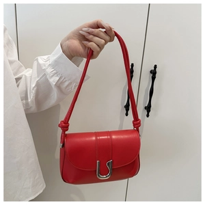 Detailed shot of vibrant red leather shoulder bag featuring a silver U-shaped metal buckle