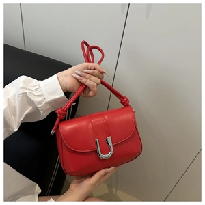 Close-up of red rectangular crossbody bag featuring a silver U-shaped metal buckle detail