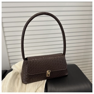 Détail de la texture tressée marron foncé du sac porté épaule avec boucle carrée dorée