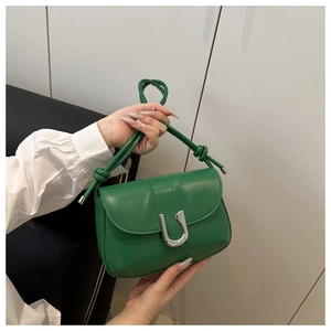 Detail of emerald green leather crossbody bag with silver U-shaped metal clasp buckle