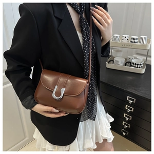 Close-up of brown leather crossbody bag with silver U-shaped metal buckle and matte finish