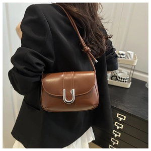 Brown leather crossbody bag with silver U-shaped clasp and knotted strap detail