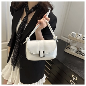 Detail showing white leather handbag with silver U-shaped clasp and buckle strap on models arm