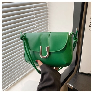Detailed shot of green leather handbag featuring a silver U-shaped buckle and knotted strap