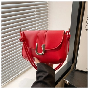 Detail of red leather shoulder bag with silver U-shaped metal buckle and decorative knots