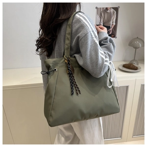 Olive green nylon tote bag detail with striped fringe charm and adjustable drawstring side