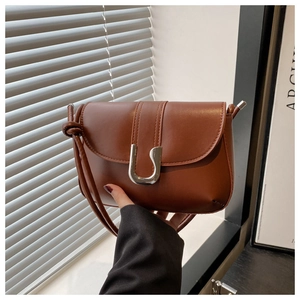 Close-up of brown PU leather crossbody bag featuring a chunky silver U-shaped metal clasp