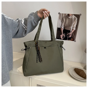 Detail of olive green nylon tote bag featuring drawstring buckle and striped tassel charm
