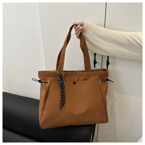 Detail of brown tote bag showing dual handles, magnetic closure, and unique knot ornament