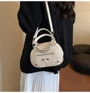 Macro view of cream crocodile-embossed leather bag with silver chain and stud details