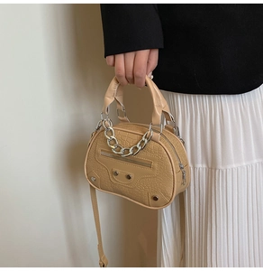 Close-up of beige crocodile texture shell bag with silver chain and metallic hardware details