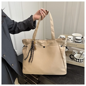 Close-up of beige nylon tote bag with side drawstrings and striped decorative charm