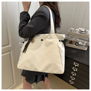 Detailed view of white large capacity tote bag with drawstring sides and black metal button