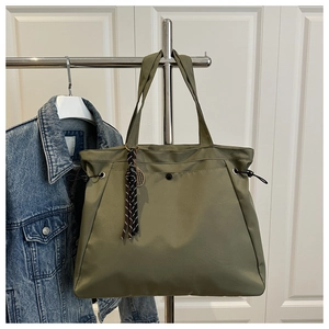 Detail of army green nylon tote bag featuring side drawstrings and a stylish tassel charm