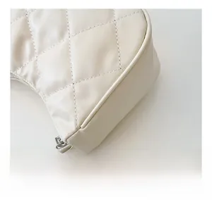Macro shot of white quilted shoulder bag featuring silver chain strap and stitching detail