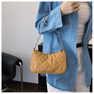 Close-up of quilted mustard yellow shoulder bag with silver chain strap details