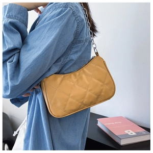 Detailed view of yellow quilted texture and silver chain strap on fashion shoulder bag