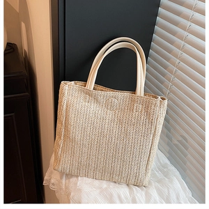 Detail of hand-woven straw tote with premium beige leather handles on lace background