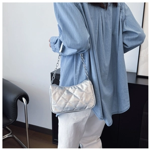 Macro detail of silver quilted underarm bag with metallic finish and chain strap