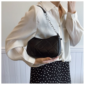 Black quilted crescent shoulder bag shown on model with chic monochrome outfit