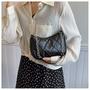 Detail shot of a black quilted underarm bag with a stylish silver chunky chain strap