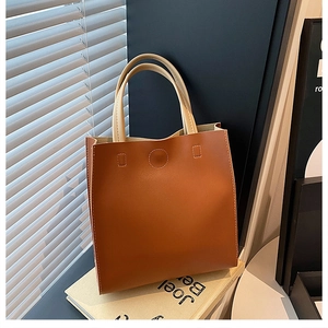 Detail view of large brown tote bag with cream handles and fine stitching on books