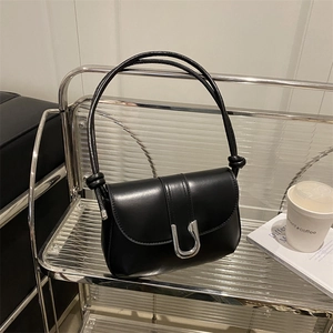 Minimalist black faux leather crossbody bag with a silver U-shaped lock and knotted strap