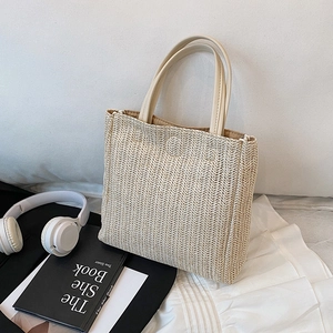 Handwoven straw tote bag with beige herringbone texture and cream leather handles