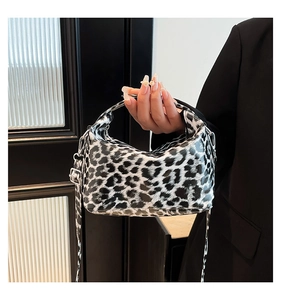 Detail of a chic leopard print handbag with glossy finish and adjustable shoulder strap