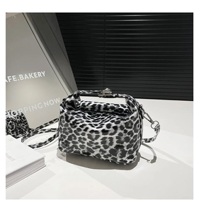 Close-up of leopard print crossbody bag with glossy finish and metal clasp detail