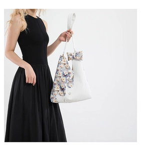 Detail of floral fabric stitching and pearl accents on a white triangular tote bag
