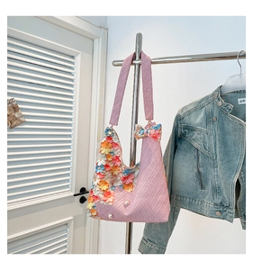 Close-up of pink woven tote bag with colorful 3D floral accents and pearl details