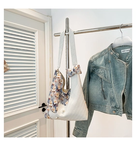 Detail of floral patchwork tote bag with pearl bow accents and woven texture
