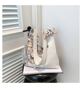 Detail of herringbone shoulder bag with floral lining, pearl accent, and bow ribbon charm